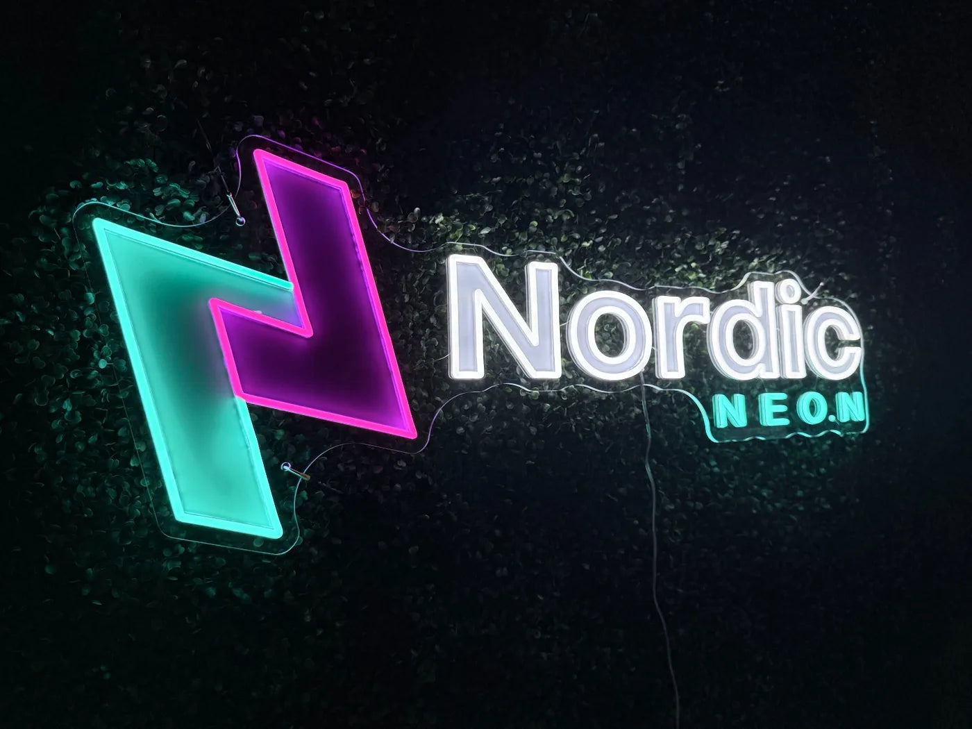 Illuminated Nordic Neon logo combining LED neon and UV print on dark green