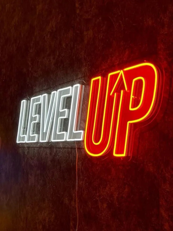 Illuminated LED neon sign LEVEL UP in white and red on a wall